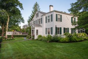 a white house with green shutters and a yard at Village Inn in Yarmouth