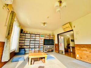 a living room with a table and a tv and books at Farm Inn Anima no Sato in Abashiri