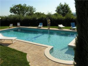 a man is standing next to a swimming pool at Villa Podere S. Gaetano in Chiusi
