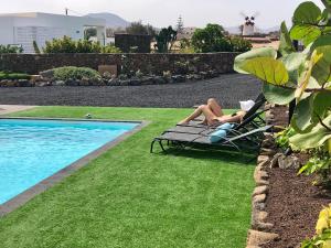 ラハレスにあるTurquesa 2 Fuerteventuraのスイミングプールの横の芝生の椅子に横たわる2名