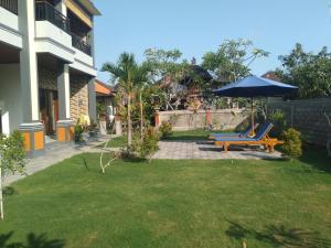un paraguas azul y un banco en un patio en Purnama 2 Homestay, en Canggu