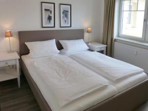 ウィトデュンにある*Strandloge*のベッドルーム1室(大型ベッド1台、白いシーツ、枕付)