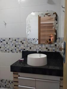 un hombre tomando una foto de un lavabo en un baño en Pousada Chalé Morada en Valparaíso de Goiás