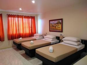 four beds in a room with red curtains at Royale House Hotel Davao powered by Cocotel in Tagum