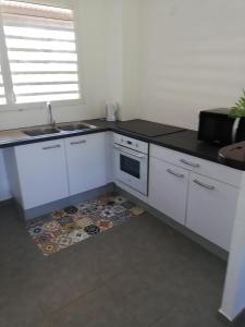 eine Küche mit weißen Schränken, einer Spüle und einem Boden in der Unterkunft Duplex Alexandra Ray Luis in Rémiré