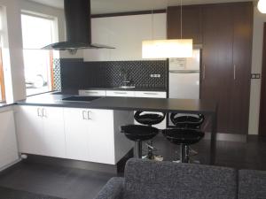 una cocina con armarios blancos y una barra con taburetes en Ártún Apartment, en Höfn