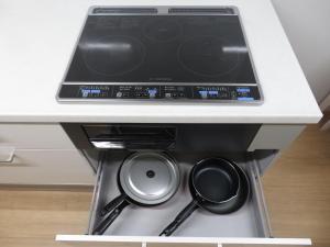a stove with pots and pans in a drawer at Utatei Nada in Takayama
