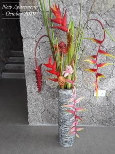 a vase with red flowers and plants in it at East Horizon Self Catering in Au Cap