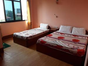 two beds in a room with two windows at Seven Steps Guest House in Muglaha