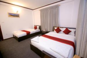 Habitación de hotel con 2 camas con almohadas rojas en Pokhara Backpackers Hostel en Pokhara