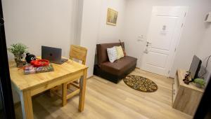 a room with a desk with a laptop and a couch at Casa Coco Hotel in Nakhon Ratchasima