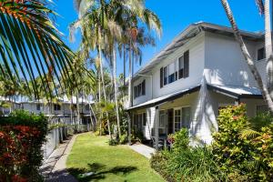 a white house with palm trees in front of it at Coco Bay Resort in Noosaville