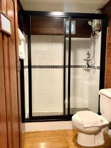 a bathroom with a shower with a toilet and a window at Riverhouse Hotel (The Teak House) in Mae Sariang