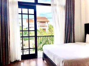 - une chambre avec un lit et un balcon avec une fenêtre dans l'établissement Riverside Impression Villa, à Hội An