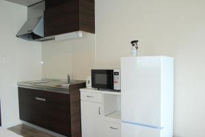 a kitchen with a white refrigerator and a microwave at Gate in Nago in Nago