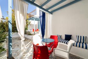 a patio with red and white chairs and a table at Fivos Apartments in Aliki