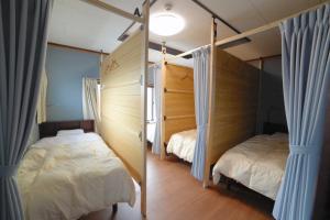 富山市にあるゲストハウス岩瀬のベッドルーム1室(ベッド2台付)、窓(カーテン付)