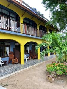 a yellow building with chairs and a balcony at Grand Beach Resort in Ko Tao