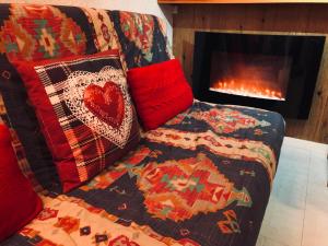 a couch with a blanket next to a fireplace at Appartement Au Pied Des Pistes in Puy-Saint-Vincent