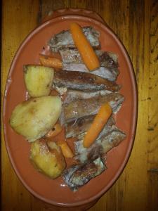 a plate of food with carrots potatoes and meat at Konoba Ognjište in Sokolac