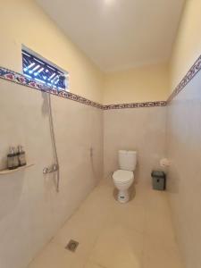 a bathroom with a toilet and a window at Kubu Taman Home Stay in Ubud