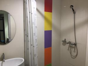 ein Bad mit einer Dusche und einer farbenfrohen Wand in der Unterkunft Highway Hotel in Chiang Mai
