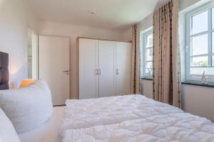ベルガーエンデ・レートヴィッシュにあるHaus Dünenroseのベッドルーム1室(白いベッド1台、窓2つ付)