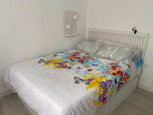 - un lit blanc avec une couette colorée dans l'établissement Marisol apartament, à Saint-Jacques-de-Compostelle