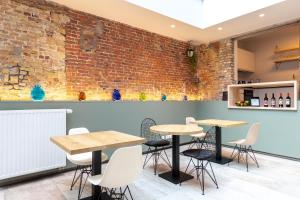 a room with tables and chairs in front of a brick wall at La Clé Brugge in Bruges