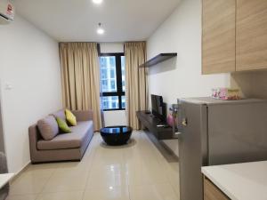 una pequeña sala de estar con sofá y nevera. en LAVENDER Suite@I_CITY, en Shah Alam