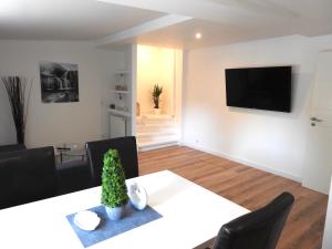 un salon avec une table et une télévision sur un mur dans l'établissement Ferienwohnung Wasserkunst, à Bad Harzburg