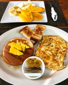 a white plate of breakfast food with eggs and fruit at Puerto Galera Hostel in Puerto Galera