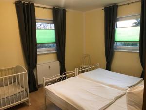 a bedroom with a bed and two windows at Ferienhaus Zur Heide - Erdgeschoss in Radibor