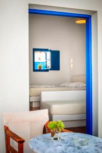 a room with two beds and a table and chairs at Aegeo Hotel in Chora Folegandros