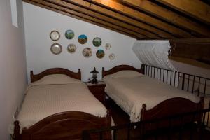 two beds in a room with plates on the wall at Xenios Cottages in Lofou