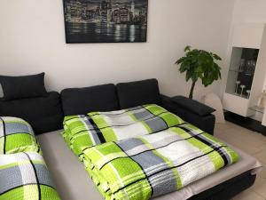 Un sofá negro con una manta verde y blanca. en Ferienwohnung Holiday Home mit Netflix en Herbolzheim