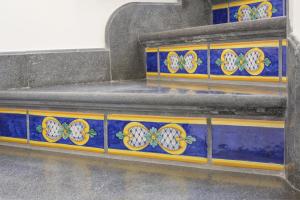 um conjunto de escadas com azulejos azuis e amarelos em Amore Rentals - Villa Il Pino em SantʼAgata sui Due Golfi