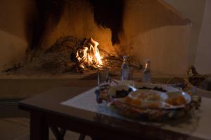 a table with a bowl of bread in front of a fire at Xenios Cottages in Lofou