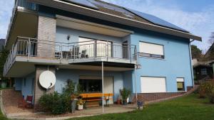 a blue house with a balcony and a table at "Morgensonne" in Halsdorf