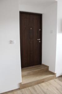 a brown door in a room with a wooden floor at M&M apartamenty in Zamość