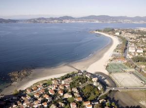 een luchtzicht op een strand met huizen en het water bij Apartamento primera línea playa d samil in Vigo