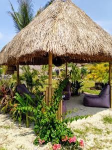 Rindi的住宿－Ecoresort Sumba Dream，灵气海滩度假村 - 带椅子和草伞
