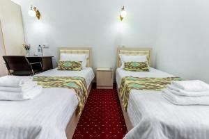 a hotel room with two beds with towels on them at Hotel Suzani Samarkand in Samarkand