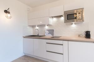 a kitchen with white cabinets and a microwave at Studio del Sol in Saint-Cyr-sur-Mer