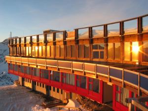 a building in the snow with the sun shining on it at Glacier Hotel Grawand in Maso Corto