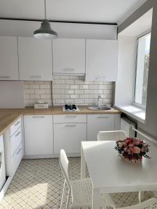 cocina con armarios blancos, mesa y sillas en Sisters apartment en Chernihiv