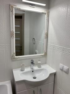 a white bathroom with a sink and a mirror at Sisters apartment UKR in Chernihiv +8 photos