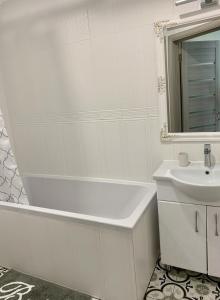 a white bathroom with a tub and a sink at Sisters apartment UKR in Chernihiv