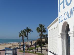 a building next to a beach with palm trees and the ocean at El Campanario in Chiclana de la Frontera