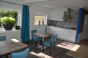 uma cozinha com uma mesa de madeira e cadeiras azuis em B&B Onder de Molen em Burgh Haamstede